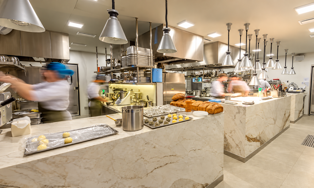 Cozinha profissional em funcionamento com chefs e coifas industriais em aço inox
